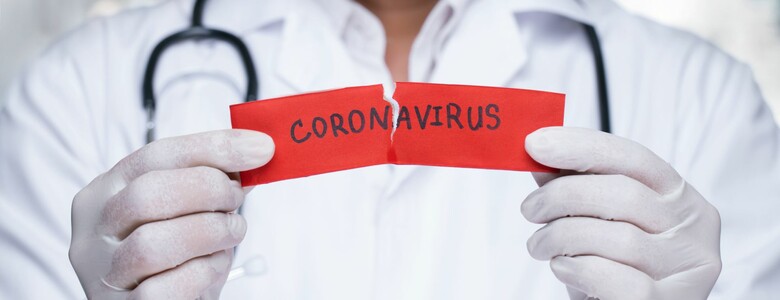 Arzt mit Mund-Nasen-Schutz mit Zettel in der Hand auf dem Coronavirus steht